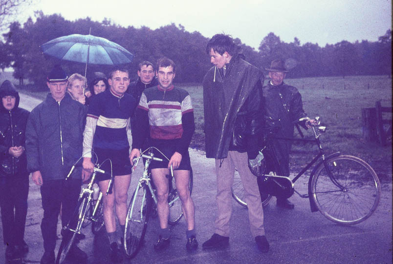 De elementen kunnen de Kuipers nimmer deren, zoals hier tijdens de clubkampioenschappen van OWC in Oldenzaal. Hennie is de linker van de twee met racefiets. De ander is Ben Wigger. Verder van links naar rechts: onbekend, Alfons Oortman, Ine Nolten met paraplu, Thea de vriendin van Bennie, broer Bennie, Wim Horsthuis en vader Gerard Kuiper met de fiets – het goede voorbeeld – aan de hand