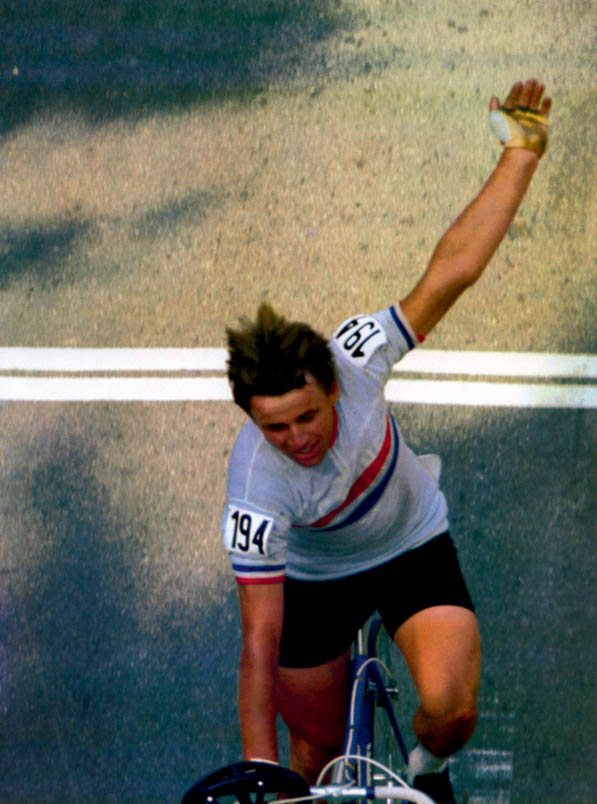 Number 194 is Olympic champion! Hennie Kuiper crosses the finish line in Munich with his arm raised. If you look closely, you can see that he is wearing a 'Ketting' shirt under his Olympic jersey. The letters 'Ketting' are partially visible behind the red and blue stripes on the Dutch shirt.