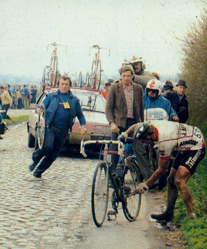 Hennie Kuiper takes his bike and tries to loosen the rear wheel, because Fred De Bruyne is coming with a new wheel.