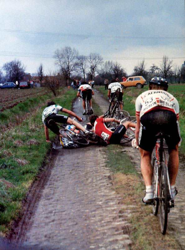 Crucial turning point in the race. Francesco Moser and Gilbert Duclos-Lassalle push hard as Alain Bondue, Patrick Versluys, Ronan De Meyer, and Marc Madiot closely inspect the cobblestones behind them. Kuiper manages to avoid a fall but has to wait with one foot on the ground before he can start chasing Moser and Duclos-Lassalle.