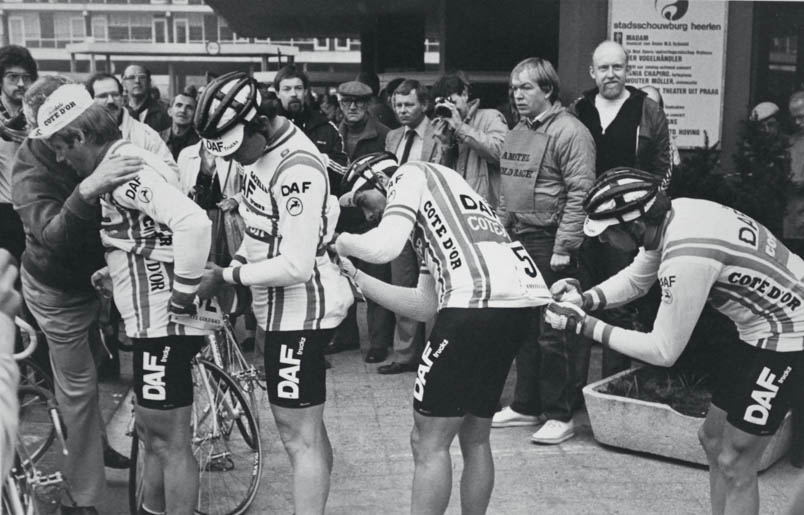 Voor de start van de Amstel Gold Race 1981 spelden de DAF-coureurs op de stoep van de Stadsschouwburg in Heerlen elkaar het rugnummer op. Hennie Kuiper wordt geholpen door René Martens, die wordt geholpen door Luc Colijn, die wordt geholpen door William Tackaert