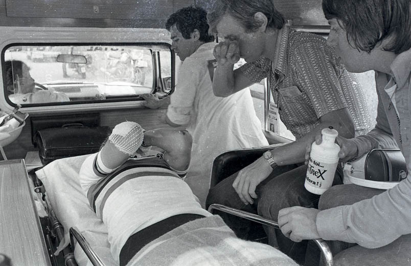 Gérard Porte, die zich het zweet van het gezicht wist, en Peter Bonthuis, helemaal rechts, gaan met Hennie Kuiper mee in de ambulance