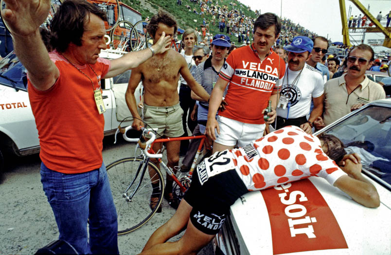 Fully 'worn out', Michel Pollentier collapses on the hood of a car after climbing l'Alpe d'Huez. His team leader Fred De Bruyne (left) tries to defuse the situation with theatrical gestures.