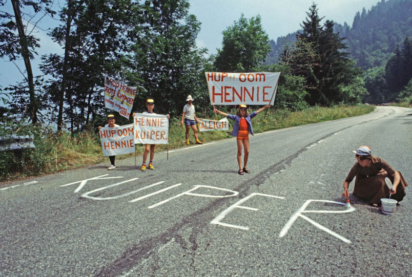 Hennie Kuiper is exceptionally strong in the Tour de France of 1978. The family gives him a heartfelt boost in the Alps: ‘Go Hennie / Great Champion / Do it again today.’ On the right, sister Maria chalks Hennie's name on the road. In the middle of the road, niece Miriam. On the left, Hennie's nephews, Anton and Ronald Kuiper.