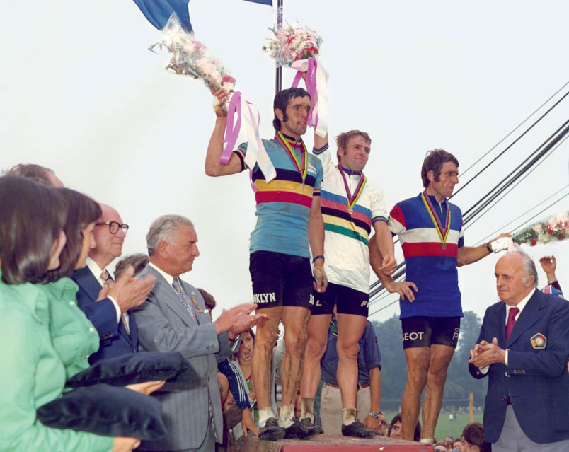 Midden tussen de weilanden, op een podium langs de weg, dringt eindelijk het besef in de vorm van een glimlach door bij Hennie Kuiper. Bloemen, een gouden medaille en de regenboogtrui: het is echt waar – wereldkampioen!